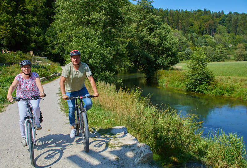 Eine Frau und ein Mann fahren Fahrrad entlang des Flusses Pegnitz.